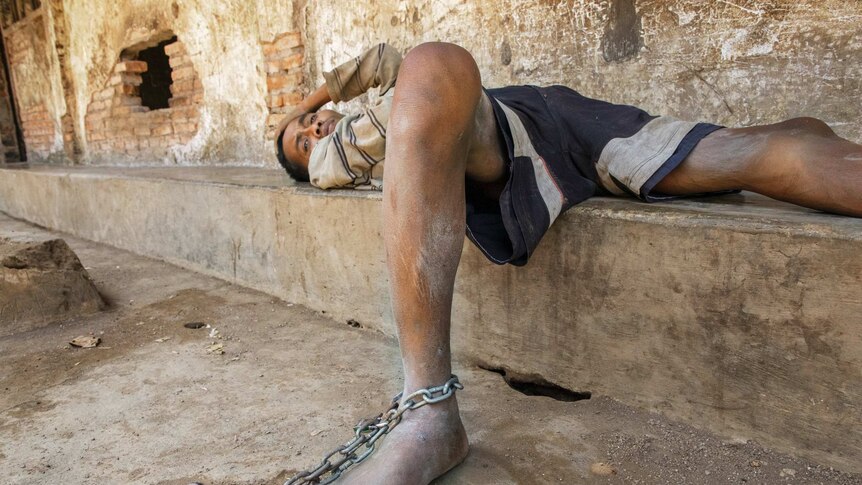 A man shackled to a bench in Indonesia.