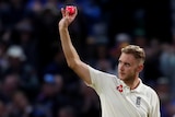 Stuart Broad holds up a pink cricket ball with his right hand to the crowd against West Indies.