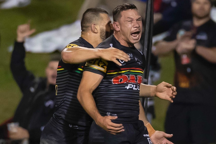 A Penrith NRL player screams out as he is hugged by a teammate after scoring a try against the Sydney Roosters.