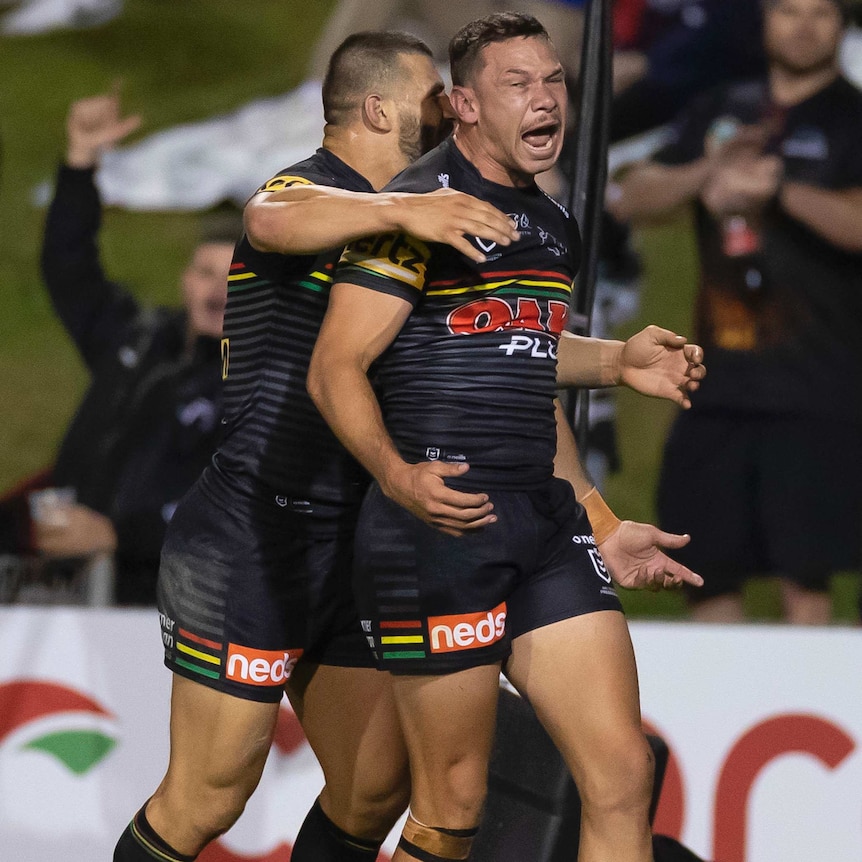 A Penrith NRL player screams out as he is hugged by a teammate after scoring a try against the Sydney Roosters.