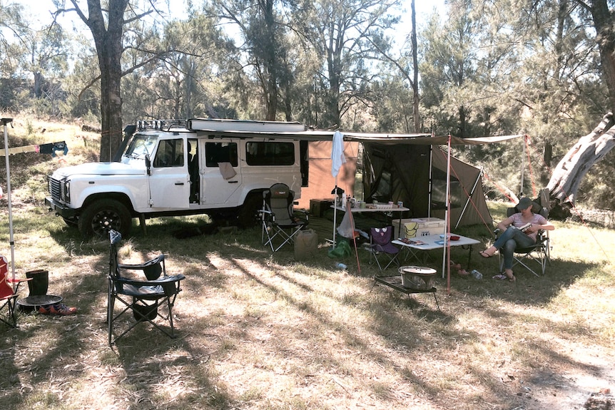 A four wheel drive vehicle at a camp site, with a tent enclosure attached at the side.