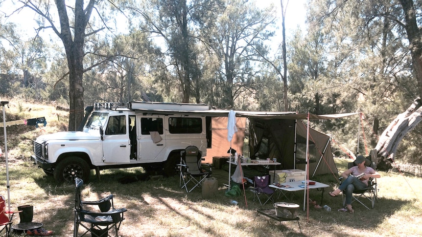 A four wheel drive vehicle at a camp site, with a tent enclosure attached at the side.