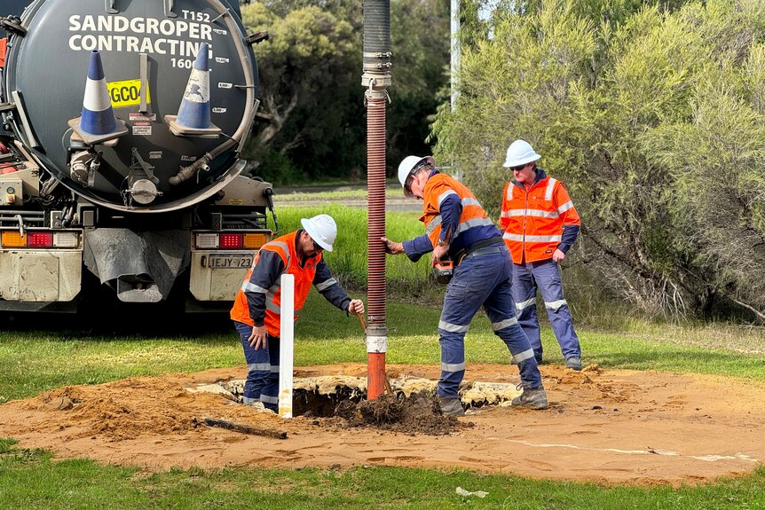 Two men and a water pipe from the ground.