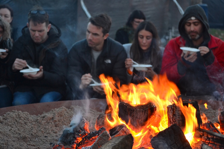 Tasmanians eat Indigenous food around a fire