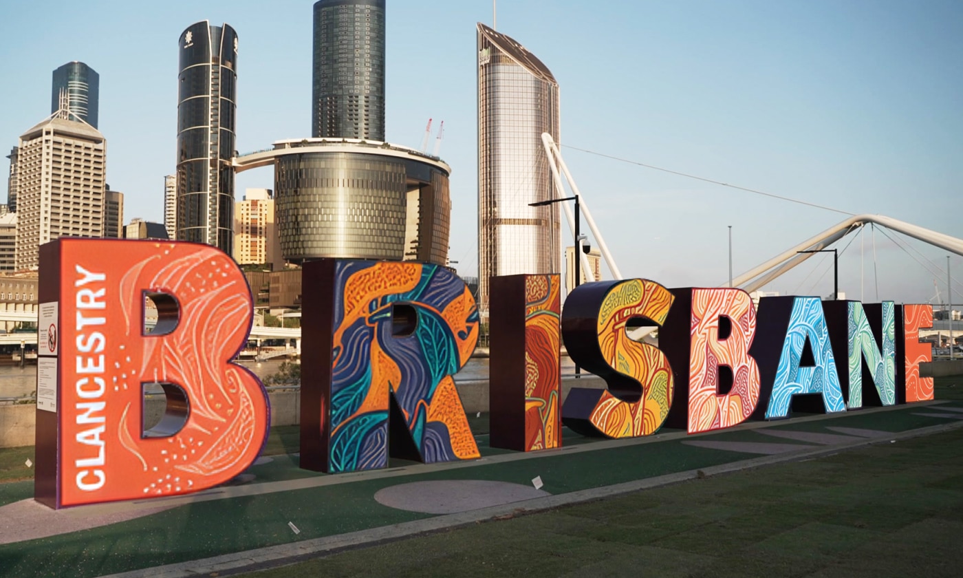 Brisbane sign in front of the city with Indigenous art on the lettering
