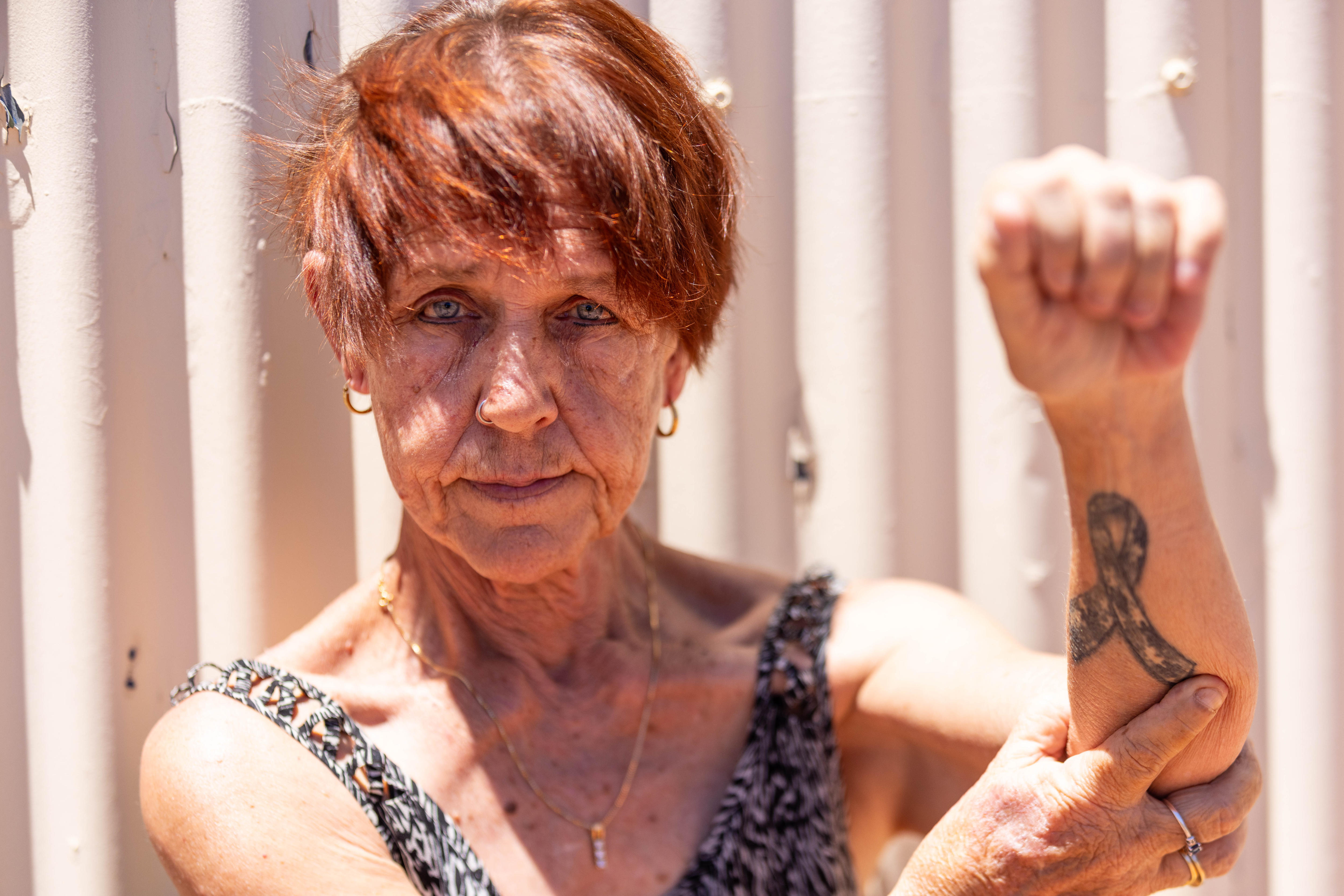 Una mujer señala un tatuaje en su brazo izquierdo.  