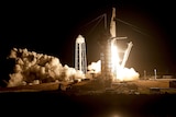 A rocket takes off from launch pad at night with a huge plume of smoke and fire.