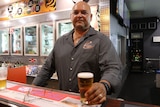 A bartender stands holding a beer.