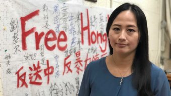 A woman stands in front of a banner reading Free Hong Kong.