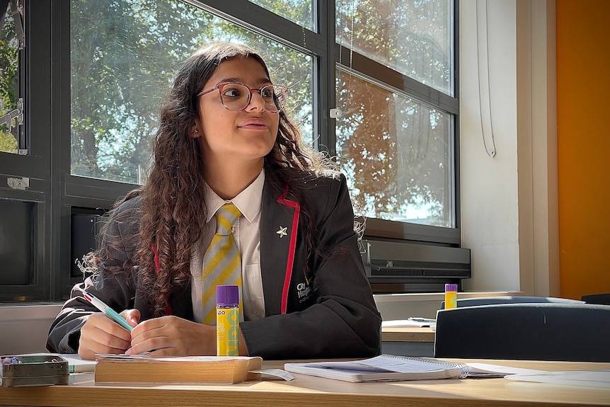 A schoolgirl takes notes at her desk during class.