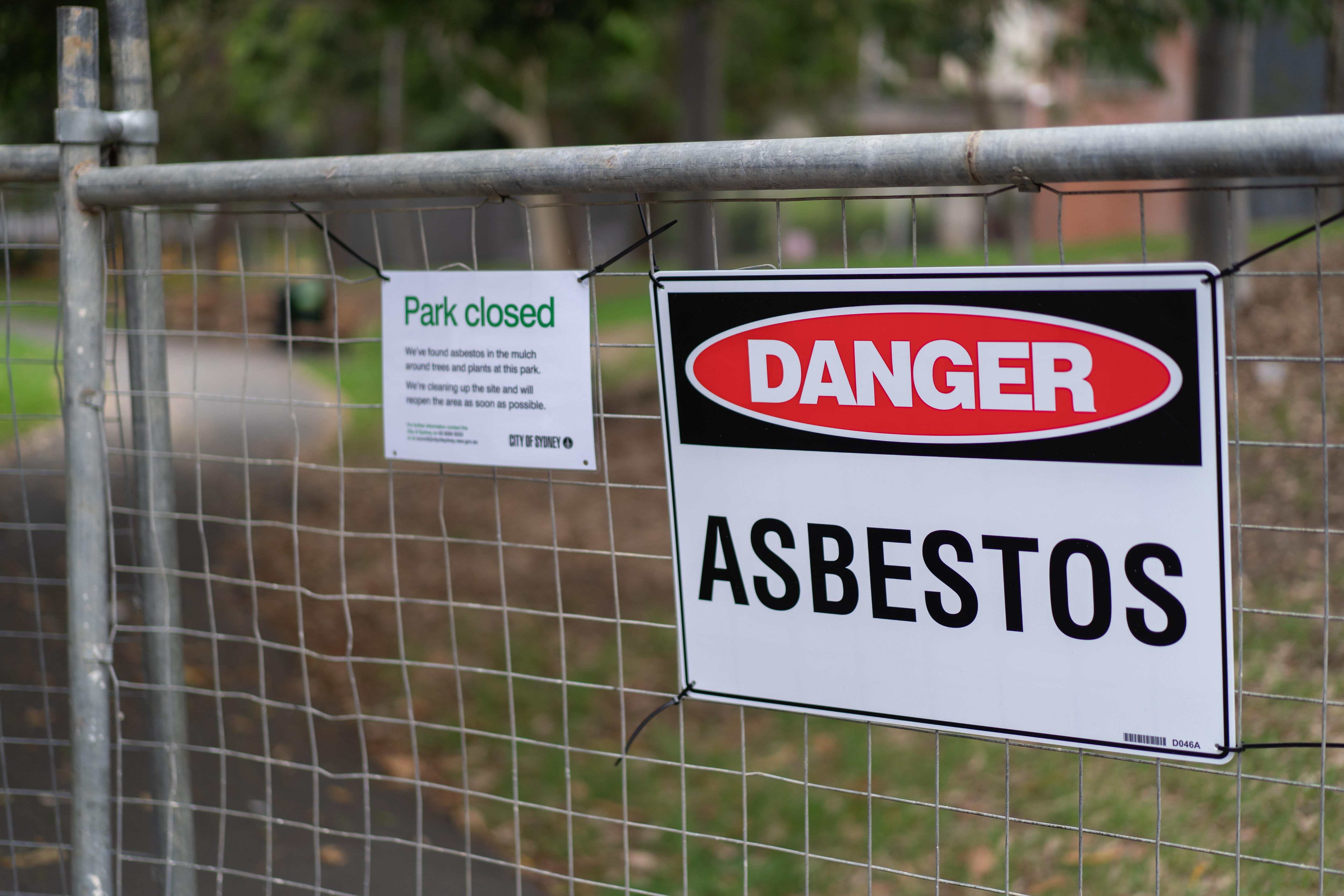 A sign on a fence says 'asbestos'.