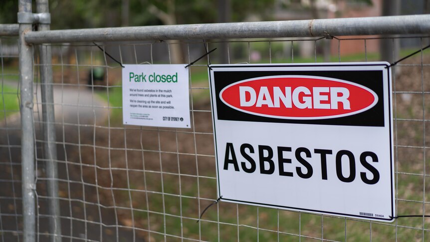 A sign on a fence says 'asbestos'.