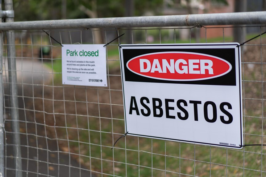 A sign on a fence says 'asbestos'.