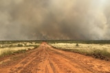 a red dirt road leading to smokey skies