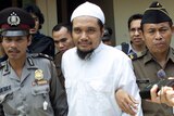 Militant cleric of Jamaah Islamiyah is escorted by security officers after a trial in this 2003 photo.