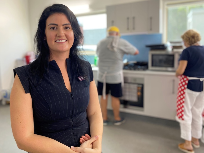 Woman with dark hair and corporate dress sits in a commercial kitchen