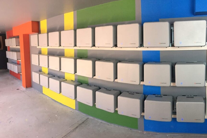 An array of 36 electricity storage batteries along a wall.