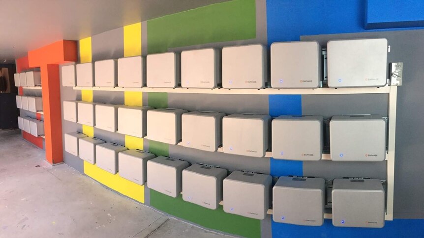 An array of 36 electricity storage batteries along a wall.