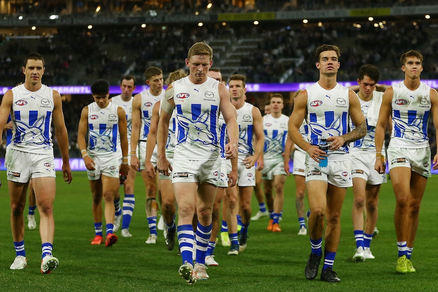 A group of North Melbourne AFL players leave the field during a match against Fremantle.