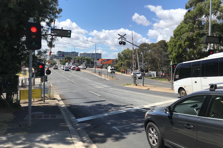 Cars stopped at a red light, before a level crossing.