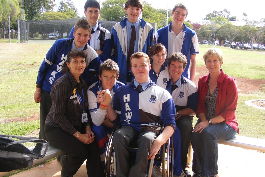 A man in a wheelchair surrounded by his classmates