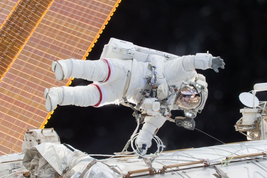 Scott Kelly floats sideways in space in an astronaut suit.