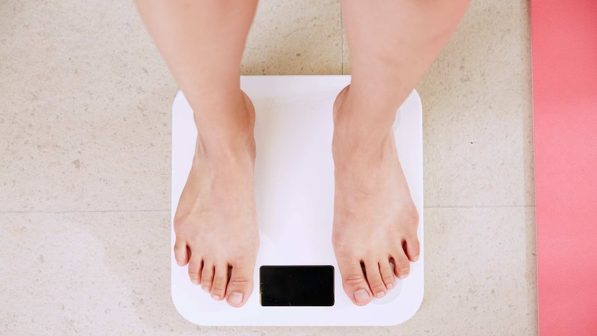View of lower legs and feet when standing on a bathroom scale