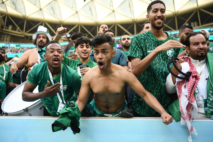 football fans in green shirts celebrating.