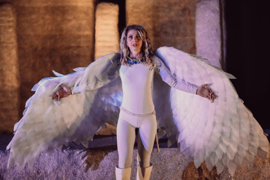 An actor dressed as an angel in front of Stonehenge replica. 