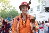 woman with hat leading a parade wearing town crier garb