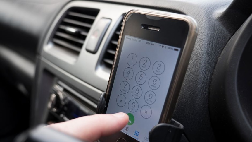 A mobile phone in a cradle on a car dash