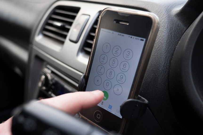 A mobile phone in a cradle on a car dash