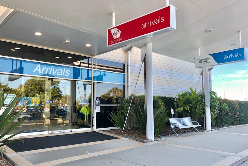 Large double sliding doors from the outside of an airport, along with signs that say "arrivals".