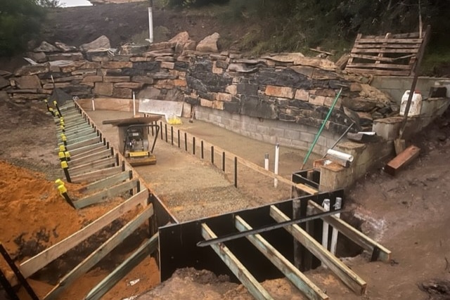 foundations and wooden scaffolding of a pool being builit into hill side 