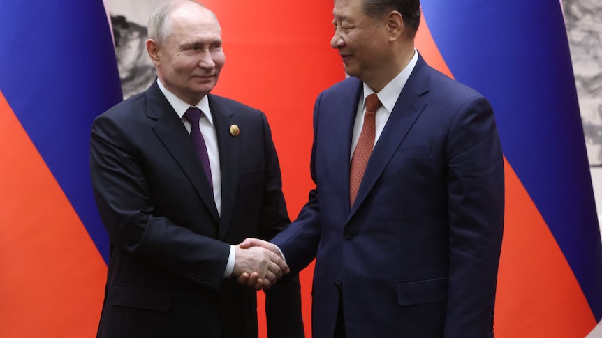 President Putin & President Xi shake hands smiling in front of their national flags