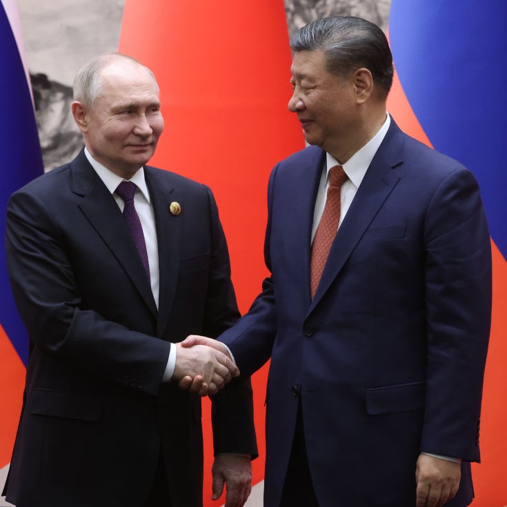 President Putin & President Xi shake hands smiling in front of their national flags