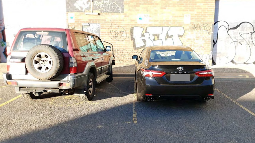 A black car parked near a brick wall.