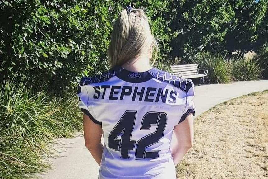 A woman in an American football jersey, as seen from behind.