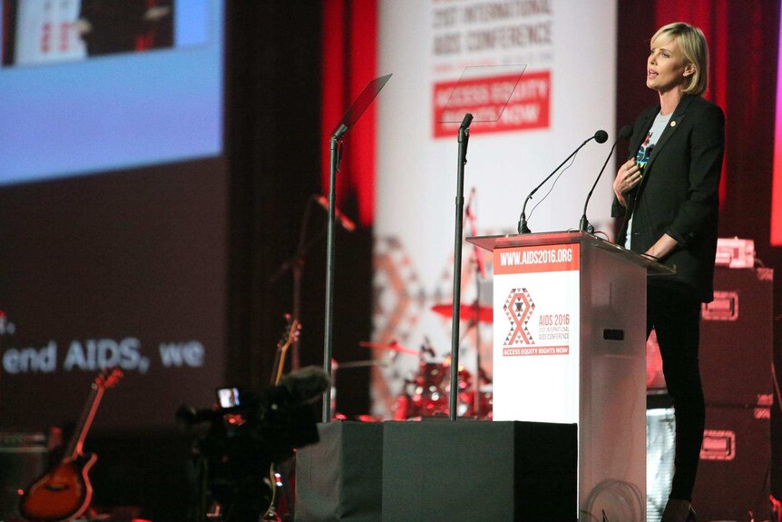Charlize Theron delivers a speech from a podium at AIDS2016.