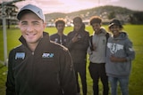 Will Smith stands on a soccer field with four teenage boys behind him.