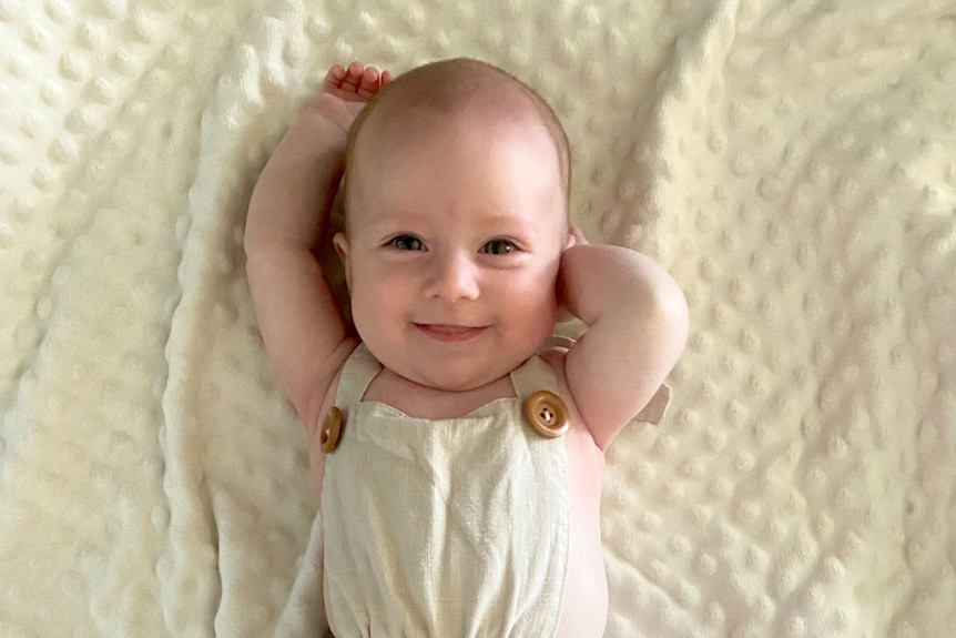 A smiling baby on a white rug.