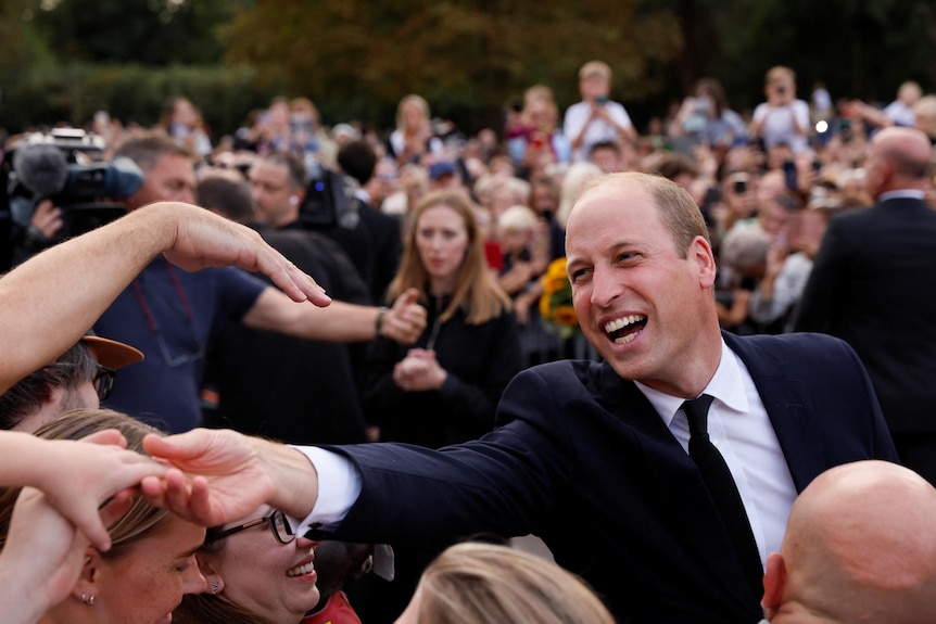Prince William smiles as he greets people outside Windsor Castle.