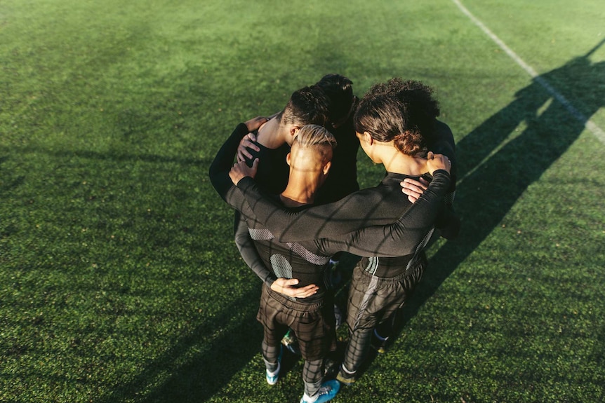 Team of soccer players huddle on a field