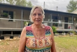 A woman in a colourful top standing in front of a house