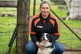 Peta Bauer sits in front of a farm gate with her border collie Jed.