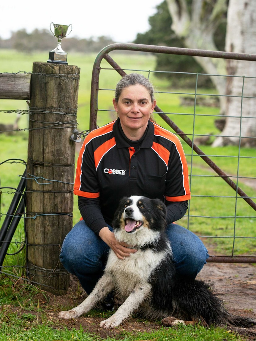 Peta Bauer sits in front of a farm gate with her border collie Jed.