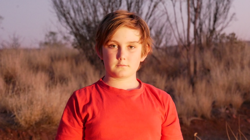 Boy in red shirt looks at camera.