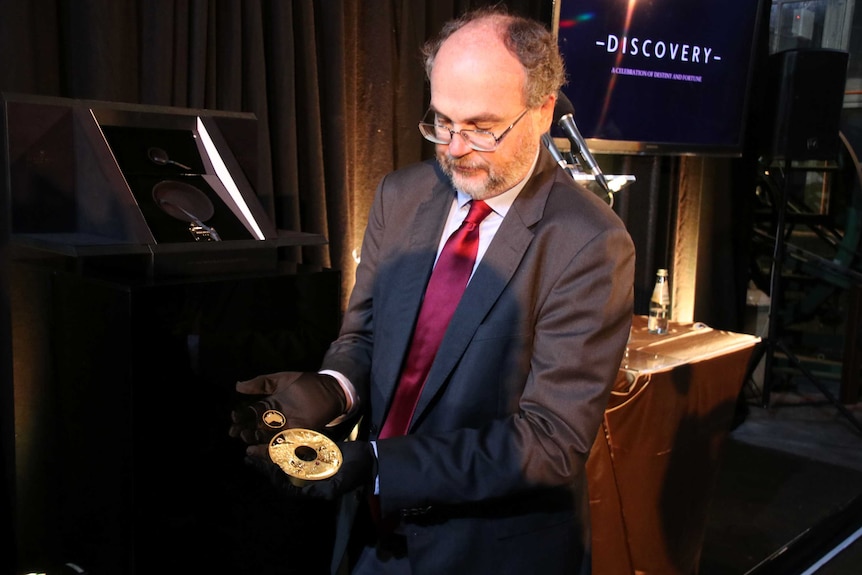 WA's Mines and Petroleum Minister Bill Johnston holds Perth Mint's $2.48 million Discovery gold and Argyle pink diamond coin.