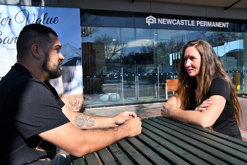 A man and a woman sitting and talking at an outdoor table on a footpath in the NSW Central West city of Dubbo