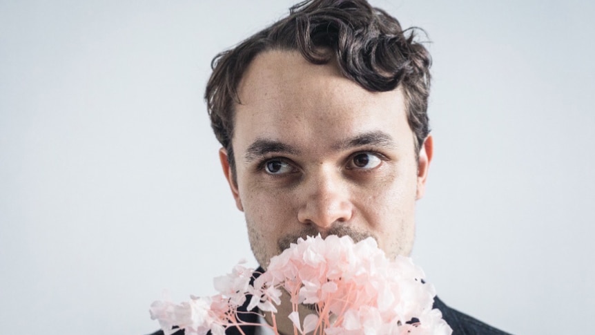 Liam Keenan holds a bunch of flowers up to his face